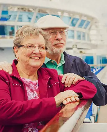 Pareja adulta mayor disfrutando la vista desde la cubierta del crucero