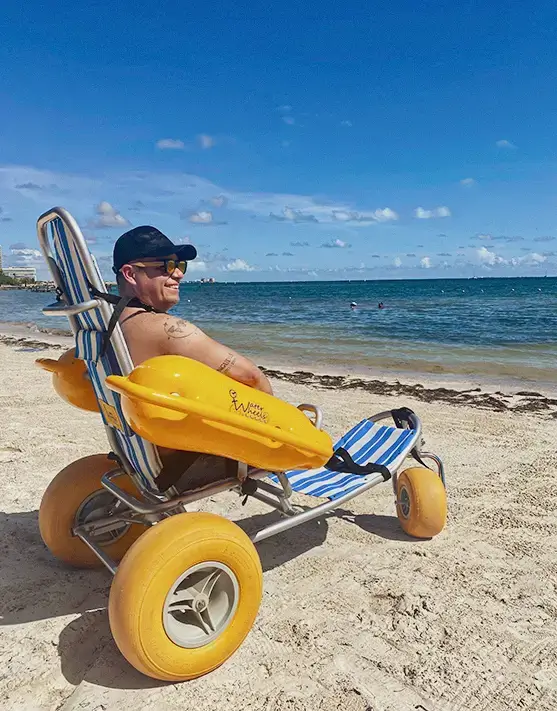 Turista en silla de ruedas de agua-arena disfrutando la playa en Cancún, Caribe mexicano